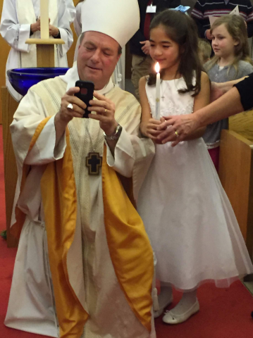 Bishop Rickel taking a selfie at a Baptism
